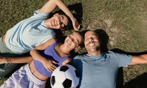 a family laying on grass with a soccer ball